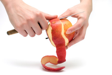Female hands peeling red apple