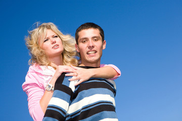 Young love couple smiling under blue sky