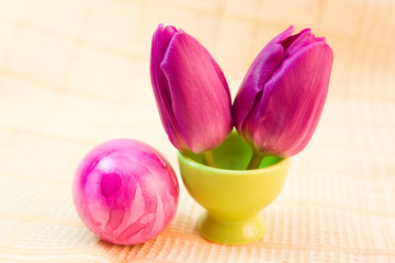 colorful easter egg and purple tulips on the table