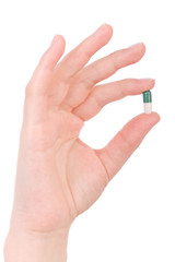 Hand holding a capsule or pill isolated on white
