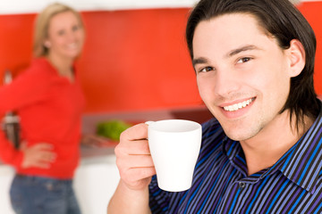 Couple in kitchen, man holding coffee cup