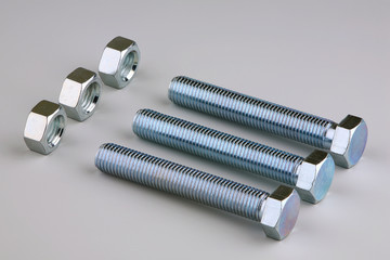 Three pairs nuts and bolts on a grey background