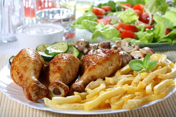 Roasted chicken legs with chips and vegetables