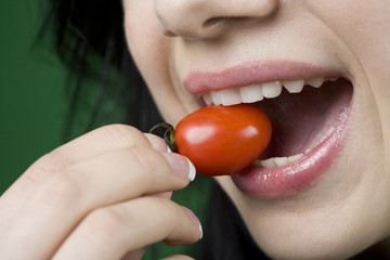 Naklejka premium Close up of woman eating cherry tomato