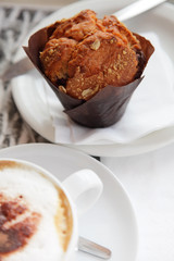 freshly made Muffin with unfocused coffee cappuchino on foregrou