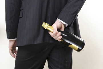 mann im anzughält hinter seinem rücken flasche sekt