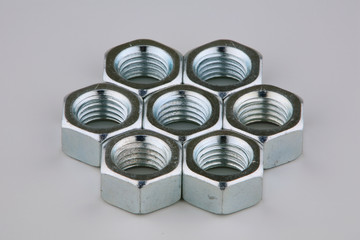 Seven metal nuts on a grey background