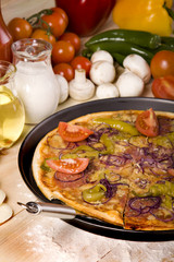 Pizza dish on wood floor with tomatos