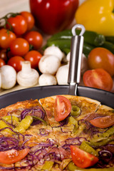 Pizza dish on wood floor with tomatos