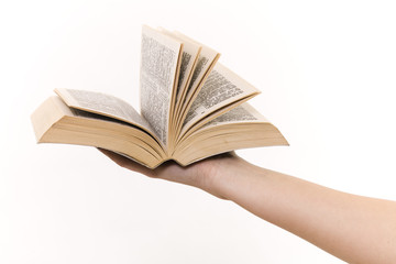 The hand holds the book on a white background