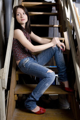 Obraz na płótnie Canvas young attractive smiling girl in jeans having a hole sitting on