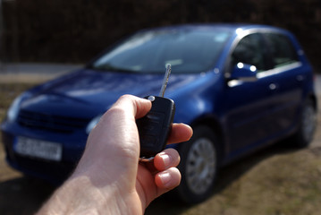 Hand holding modern car key opening new car