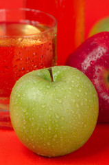 Juicy red and green apples on a red background