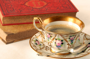 Zwei alte Bücher und eine Tasse Kaffee auf weißem Tischtuch