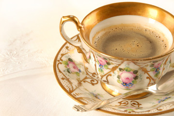 Alte Kaffeetasse mit gestickter Serviette auf weißem Tischtuch