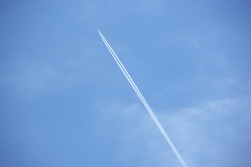 White Condensation Trail From A Jet As It Flies Across A Blue Sk