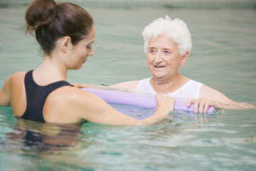 Instructor And Elderly Patient Undergoing Water Therapy - obrazy, fototapety, plakaty