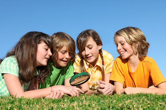 Group Of Kids At Summer Camp Playing With Magnifying Glass