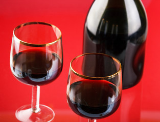 Glass of red wine with glass and bottle
