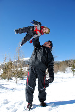 Père qui joue avec son enfant à la neige