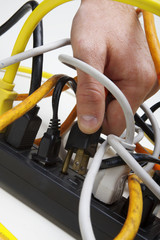 Plugging a cord into a tangled surge protector.