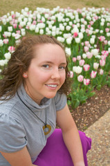 Fototapeta premium A pretty young girl poses in front of early spring flowers