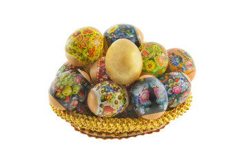 Many easter decorated eggs lying in a basket weaved from straw i