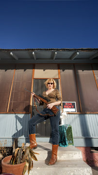 Woman on front proch with rifle
