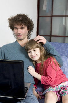 Father and daughter playing game sitting on the sofa using a lap
