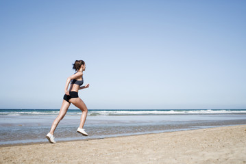 Fototapeta na wymiar Junge Frau joggt am Strand