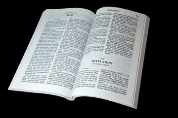 Open bible at the book of Revelation isolated on black