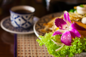 Served thai noodles with an orchid and a cup of tea