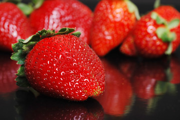 Strawberries on black with reflection
