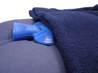 Blaue Wärmflasche eingehüllt in eine blaue Decke