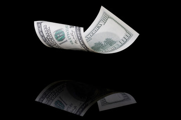 hundred dollar bill on a black background with reflection