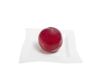 big red plum on the white plate