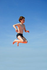 Boy jumping against blue sky