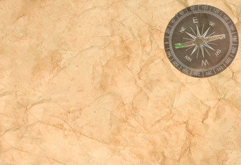 Old crumpled paper with a transparent compass in the corner