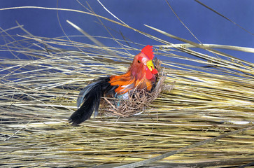 Toy bird with brass-nest on a bunch of hay