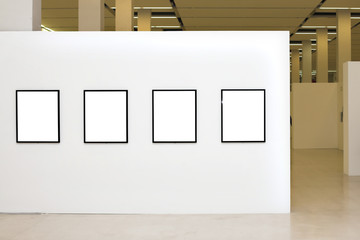 Exhibition with four empty frames on white walls