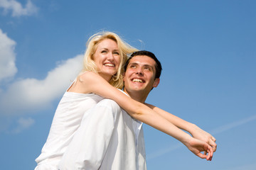 Obraz premium Young love couple smiling under blue sky