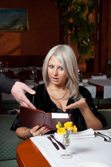 Blond girl in a restaurant show a huge bill for food