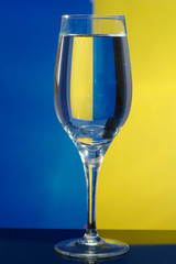 The glass  with water costs on is yellow a dark blue background