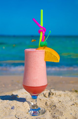 Glass of pink cocktail on the beach