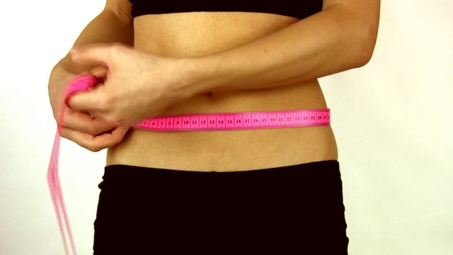 Slim young woman measuring her belly