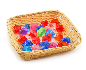 Colored assorted gemstones in wooden basket isolated