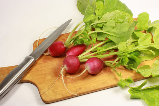 Red radish and knife over plank