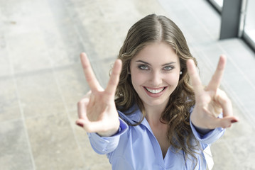 junge frau macht victory zeichen mit fingern und lacht