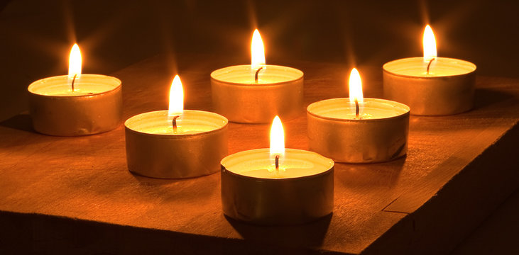 Many lighted candles on a dark background.