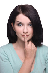 Naklejka premium Attractive brunette girl with finger on lips on white